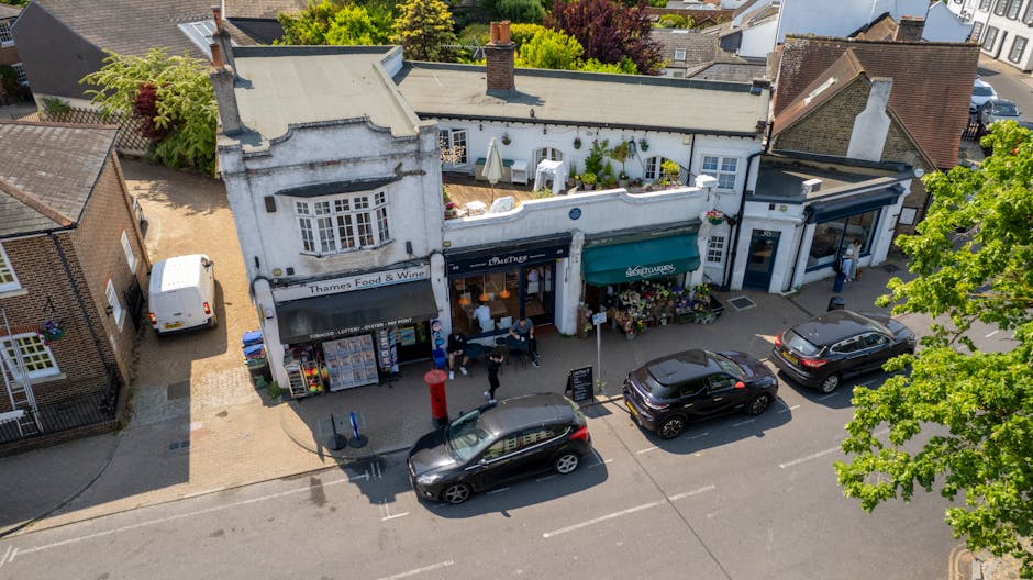 A street-level view of a building with a traditional architectural facade featuring decorative moldings and tall, rectangular windows above the entrance. The ground floor houses a retail shop named 'P